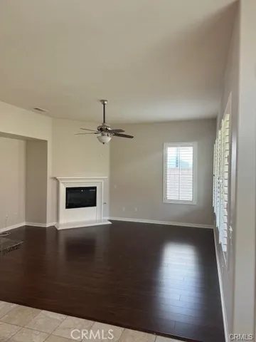 an empty room with wooden floor fireplace and windows