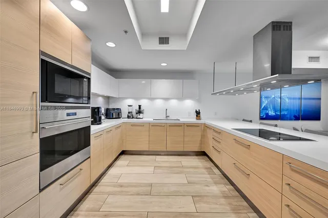 a white kitchen with stainless steel appliances granite countertop a stove a sink and a microwave