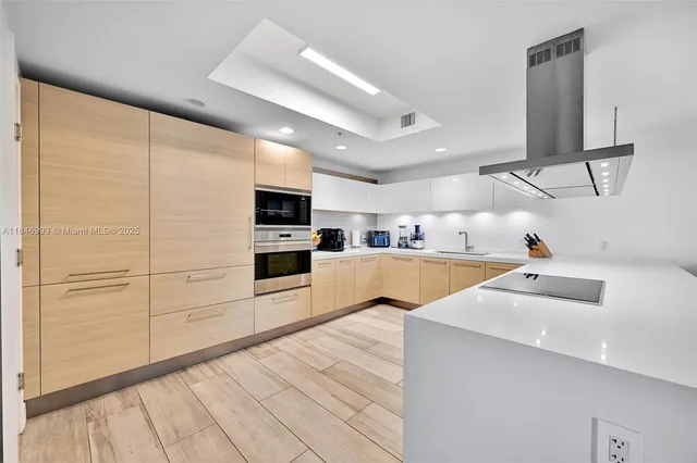 a kitchen with stainless steel appliances kitchen island granite countertop a sink and white cabinets with wooden floor