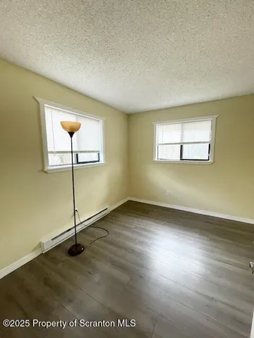 an empty room with wooden floor mirror and windows