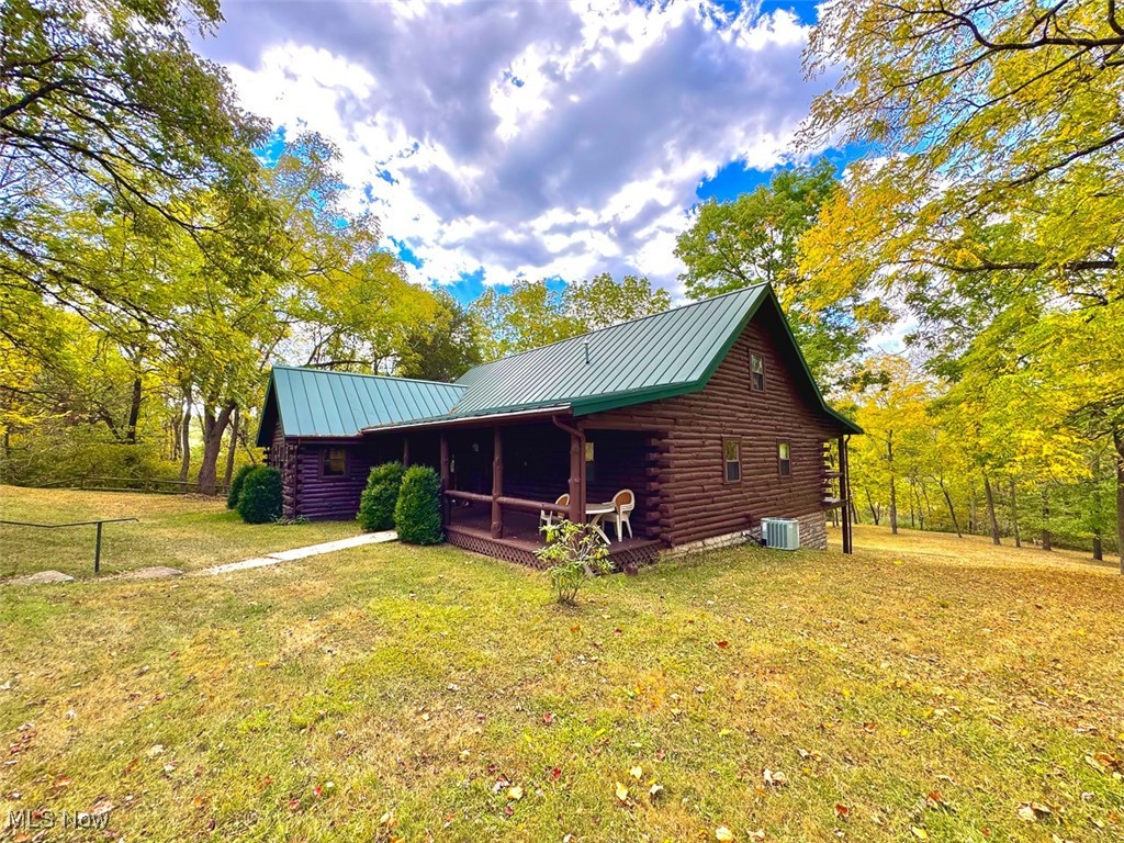 18063 Sligo Road Freeport, OH 43973 - Photo 25 of 50 View of property exterior with log exterior, a metal roof, a yard, a porch, and a standing seam roof
