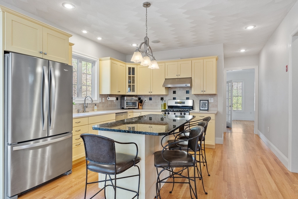 18 Danforth Lane Bolton, MA 01740 - Photo 3 of 29 a kitchen with stainless steel appliances granite countertop a refrigerator a stove a sink dishwasher a dining table and chairs with wooden floor