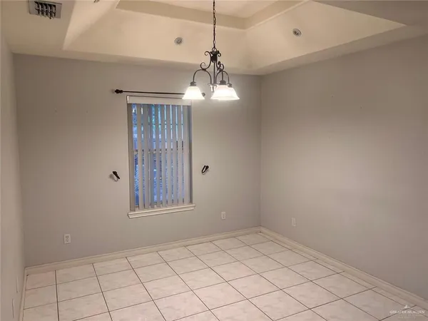 a view of an empty room with window and chandelier fan
