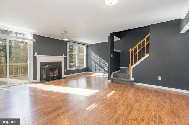 a view of an empty room with wooden floor and a fireplace