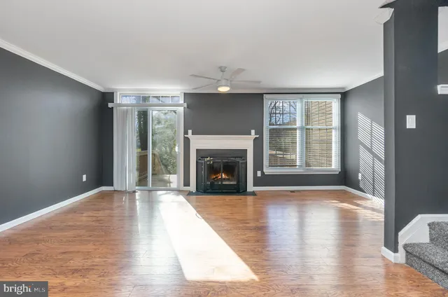 a view of an empty room with wooden floor fireplace and a window