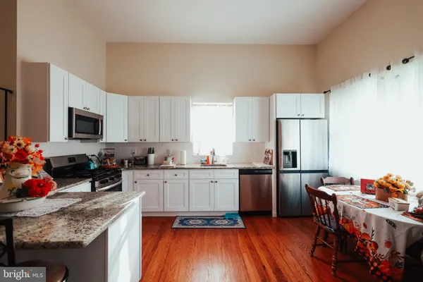 a kitchen with a refrigerator a stove a sink dishwasher with a dining table and chairs with wooden floor