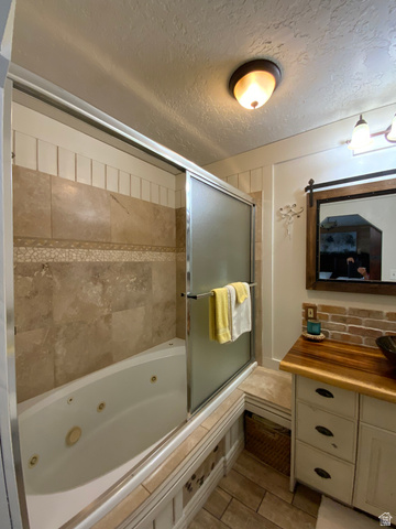 1061 Copper Street Stockton, UT 84071 - Photo 26 of 43 Bathroom featuring a jetted bathtub with a sliding glass enclosure, tile surround, wood-finish flooring, and a vanity with a wood countertop