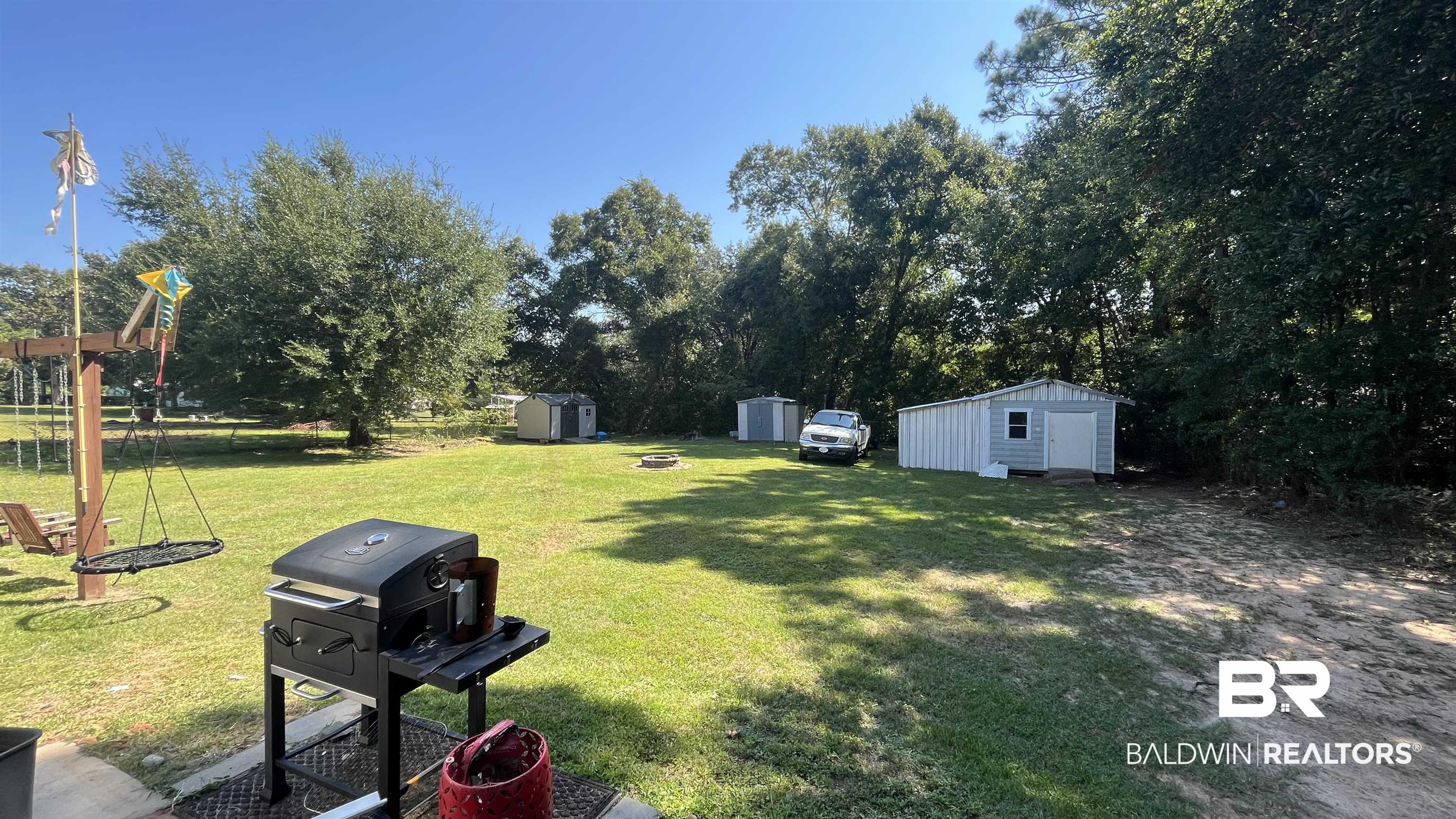 12932 Santa Piedro Street Lillian, AL 36549 - Photo 18 of 20 View of grassy yard featuring a storage unit and an outdoor fire pit