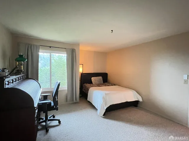 a bedroom with a bed windows and chair