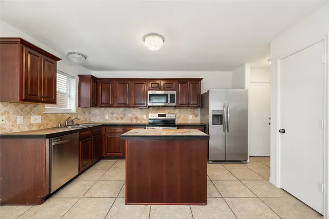 a kitchen with stainless steel appliances granite countertop a stove top oven a sink dishwasher and a refrigerator with wooden cabinets