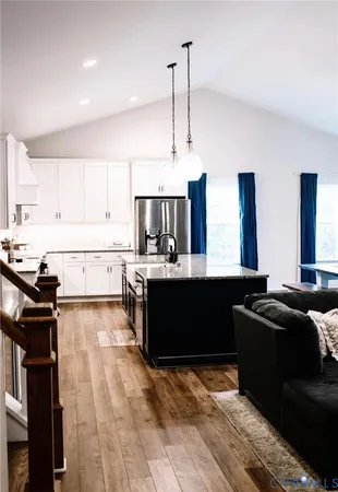 a large kitchen with kitchen island granite countertop a sink dishwasher stove and white cabinets