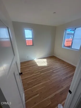 a view of an empty room with wooden floor and window