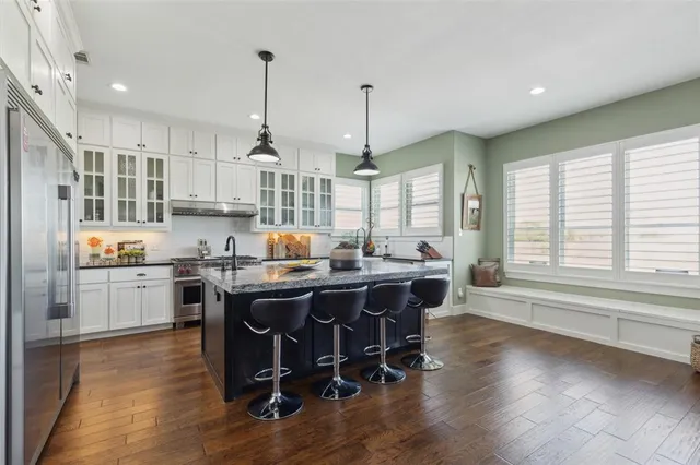 a kitchen with stainless steel appliances granite countertop a sink a stove a refrigerator and wooden floor