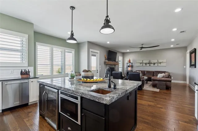 a kitchen with stainless steel appliances granite countertop a sink a stove and a wooden floor