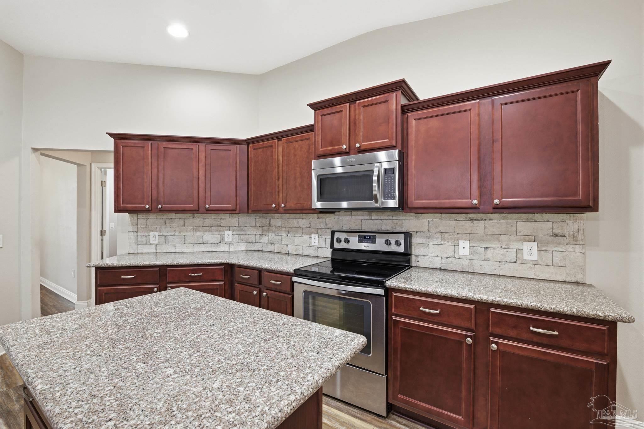 5661 Cane Syrup Circle Pace, FL 32571 - Photo 7 of 20 a kitchen with stainless steel appliances granite countertop wooden cabinets a stove a sink and dishwasher