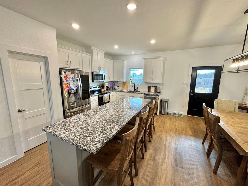 416 Austin Street Gainesville, TX 76240 - Photo 11 of 33 a kitchen with stainless steel appliances granite countertop sink refrigerator dining table and chairs