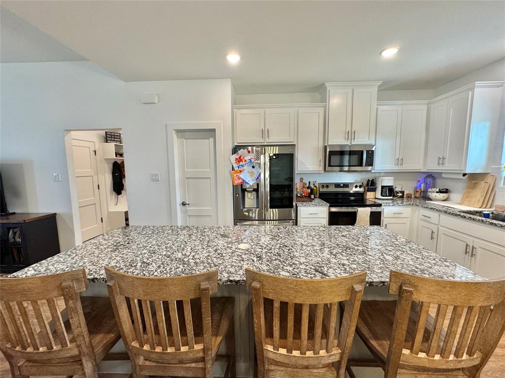 416 Austin Street Gainesville, TX 76240 - Photo 13 of 33 a kitchen with stainless steel appliances granite countertop a stove top oven a refrigerator a sink a dining table and chairs