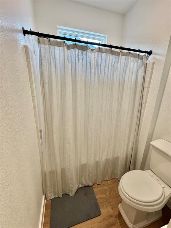 416 Austin Street Gainesville, TX 76240 - Photo 27 of 33 a bathroom with a toilet and a shower curtain