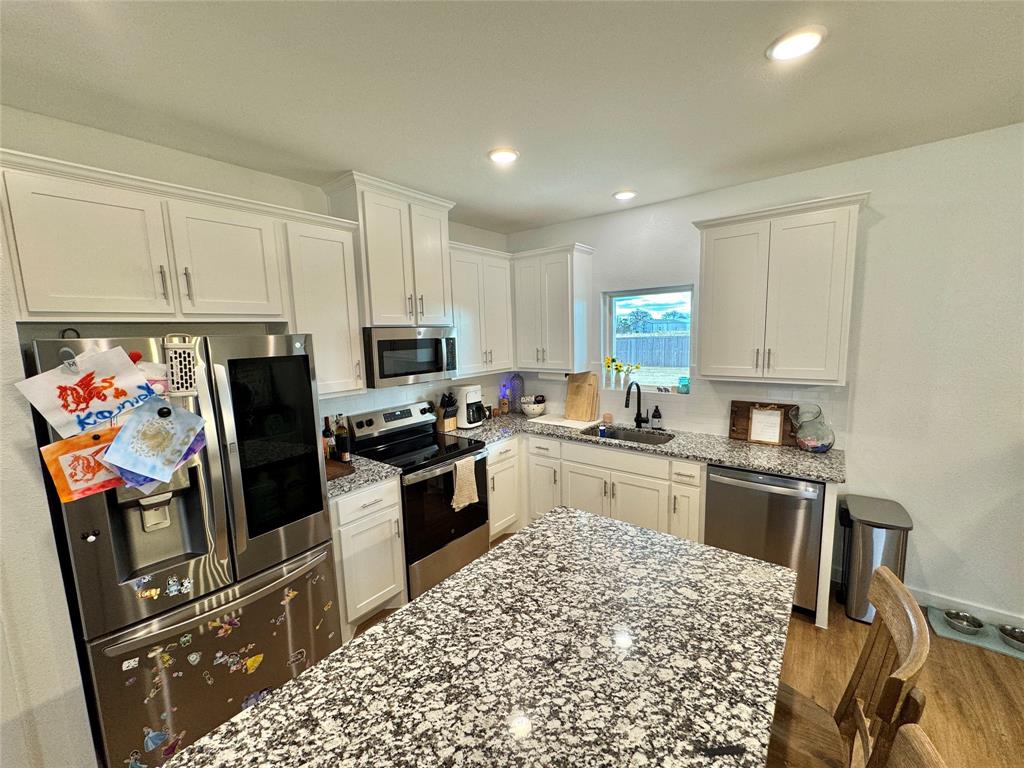 416 Austin Street Gainesville, TX 76240 - Photo 7 of 33 a kitchen with stainless steel appliances granite countertop a refrigerator stove microwave and sink