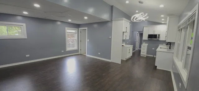 an empty room with wooden floor and a kitchen