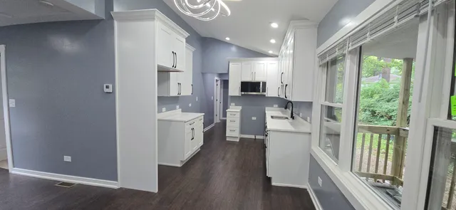 a view of a kitchen with a refrigerator a sink and dishwasher a oven with wooden floor