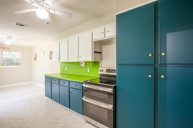a room with kitchen island a chandelier fan and cabinets