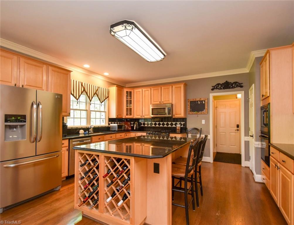 3817 Pinetop Road Greensboro, NC 27410 - Photo 14 of 29 Kitchen features tons of natural colored cabinets, double ovens, tile back splash, granite counters. There is a large walk-in pantry just through the doorway and to the left. To the right, the hallway leads to garage. Straight ahead is side entry doorway to driveway.