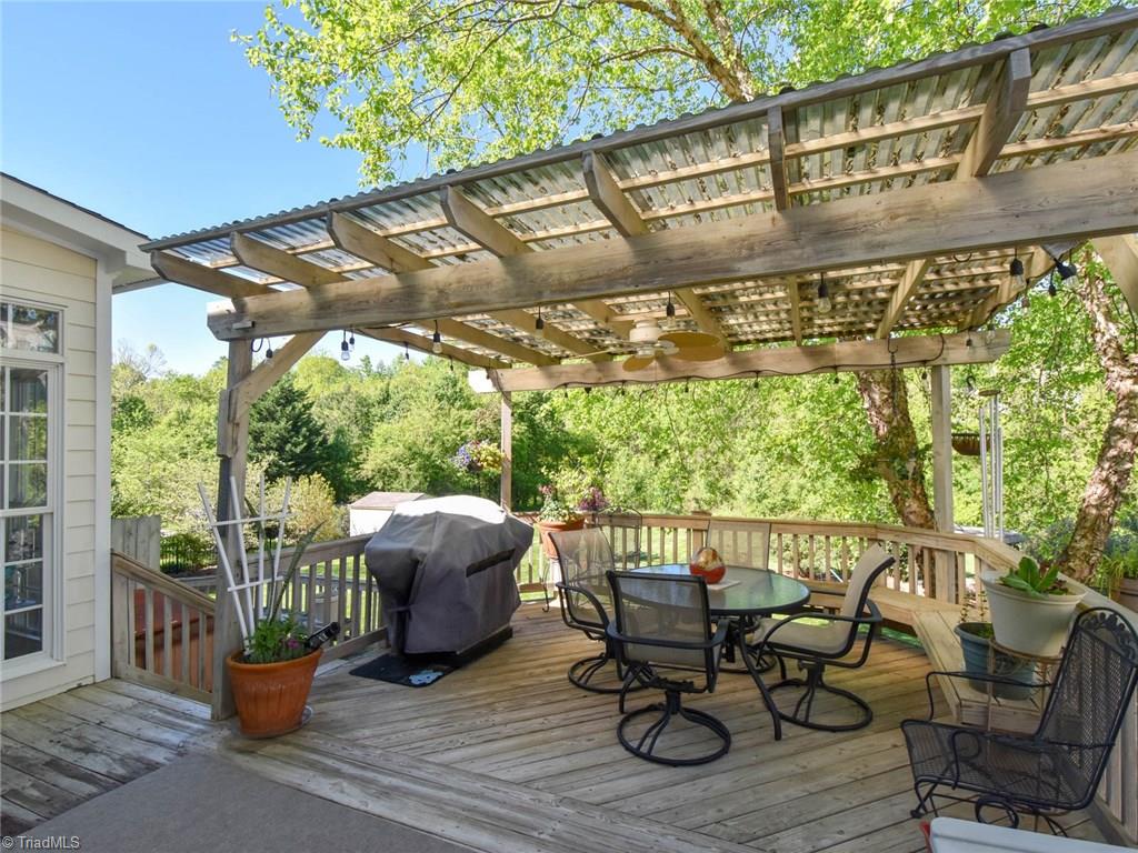 3817 Pinetop Road Greensboro, NC 27410 - Photo 26 of 29 Main level deck has covered pergola w/ceiling fan and enclosed wet bar area, perfect for outdoor entertaining. The stairs lead to the lower level deck, and then to the paver patio at ground level. Lots of play space in the back yard!
