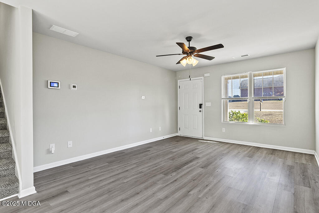 306 Mill Meadow Road Macon, GA 31216 - Photo 8 of 29 an empty room with wooden floor chandelier fan and windows