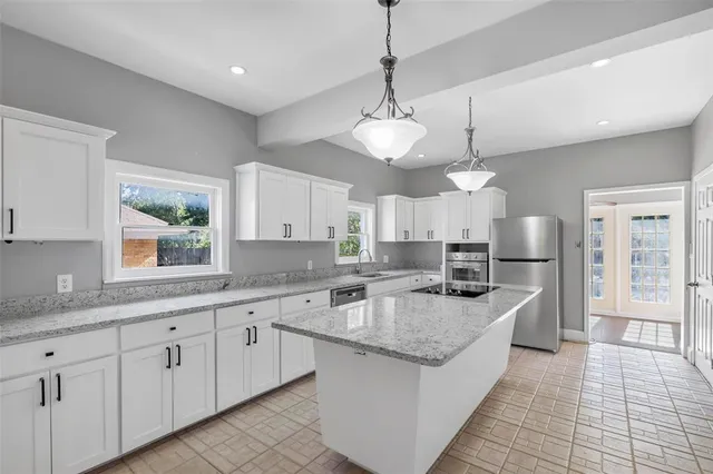 a large kitchen with stainless steel appliances granite countertop a sink dishwasher stove and white cabinets