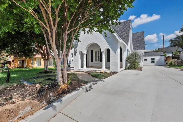 a front view of a house with garden and trees