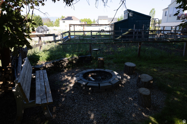 827 South 600 East Logan, UT 84321 - Photo 27 of 30 Outdoor fire pit area with gravel groundcover, wood-plank bench seating, and tree stump accents