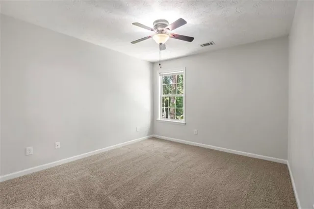 an empty room with a window and a ceiling fan