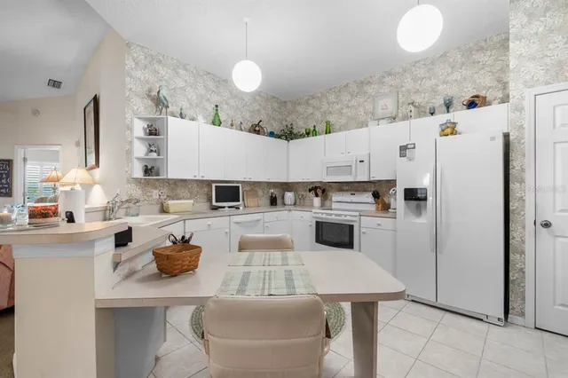 a kitchen with a refrigerator a stove a sink and white cabinets
