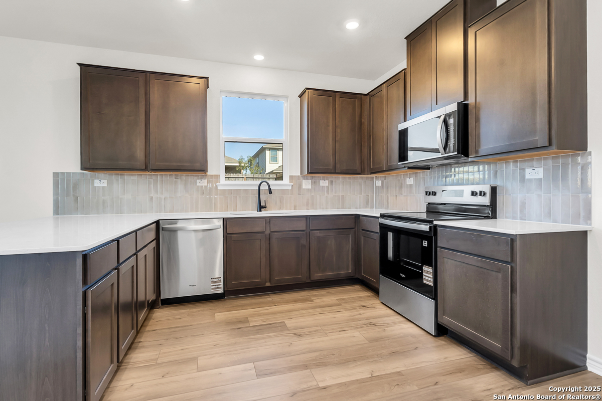 9515 Griffith Run Converse, TX 78109 - Photo 6 of 18 a kitchen with stainless steel appliances granite countertop a sink a stove a refrigerator cabinets and a kitchen island