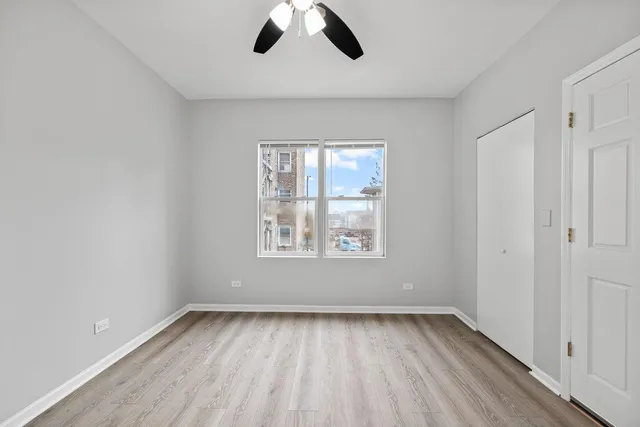 an empty room with ceiling fan and window