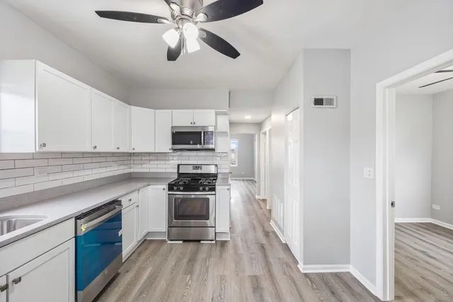 a kitchen with stainless steel appliances a sink cabinets and wooden floor