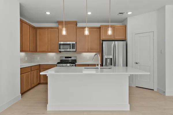 a large kitchen with stainless steel appliances granite countertop a sink a stove and a refrigerator