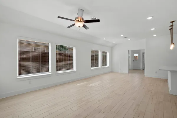 a view of an empty room with a window and wooden floor