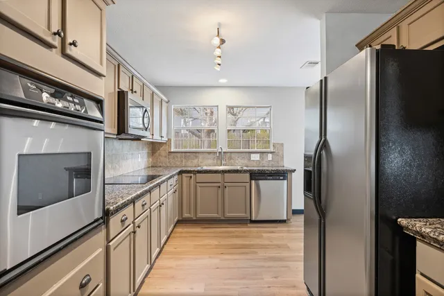 a kitchen with stainless steel appliances granite countertop a refrigerator and a stove
