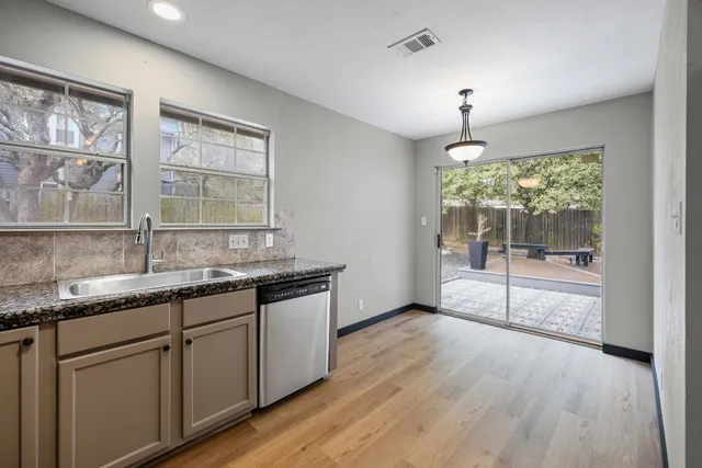 a kitchen with granite countertop a stove a sink and wooden floors