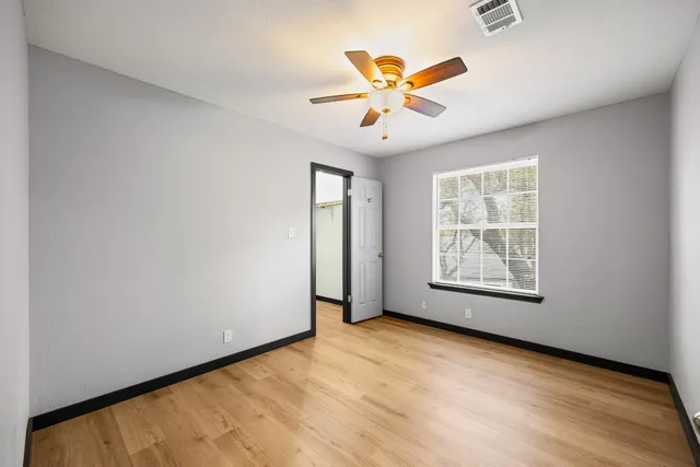 an empty room with windows and fan