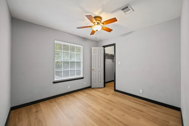 an empty room with a window and a ceiling fan