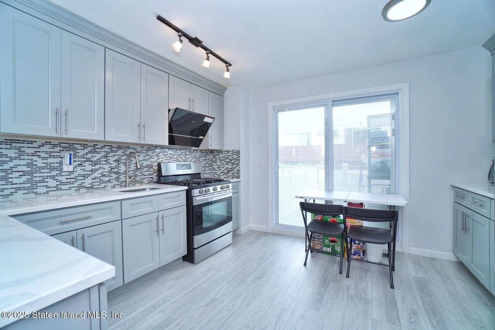 168 Rosedale Avenue Staten Island, NY 10312 - Photo 8 of 21 a kitchen with a table chairs a sink dishwasher stove and cabinets with wooden floor