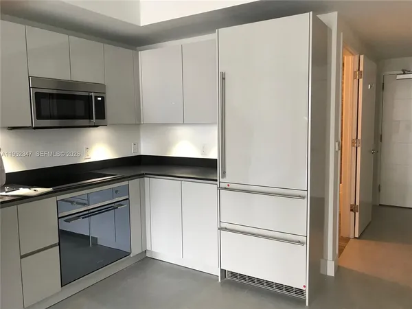 a kitchen with white cabinets and a refrigerator