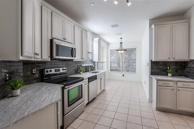 a kitchen with stainless steel appliances granite countertop a stove a sink and a microwave