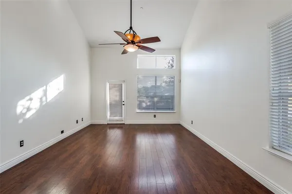 a view of a room with wooden floor a ceiling fan and windows