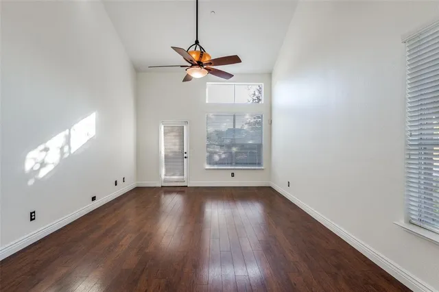 a view of a room with wooden floor a ceiling fan and windows