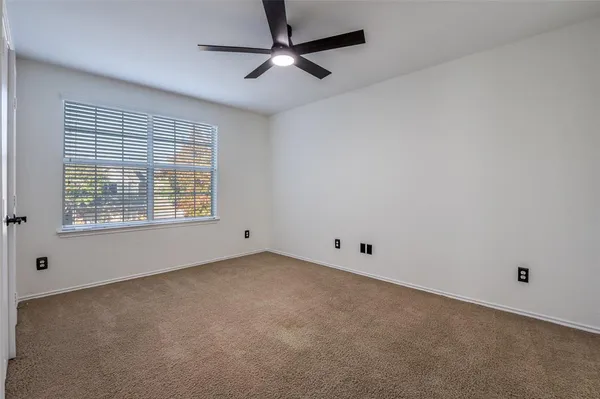 an empty room with a window and a fan