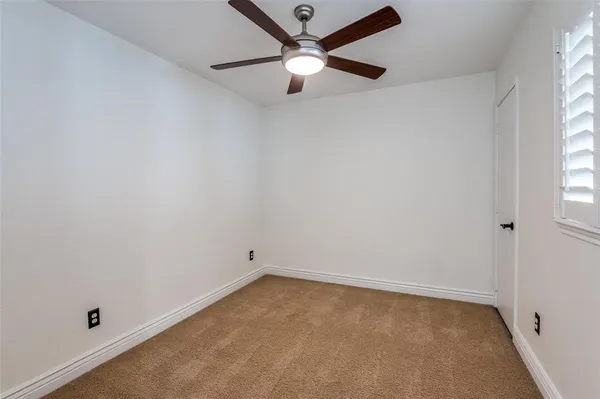 an empty room with a window and a ceiling fan